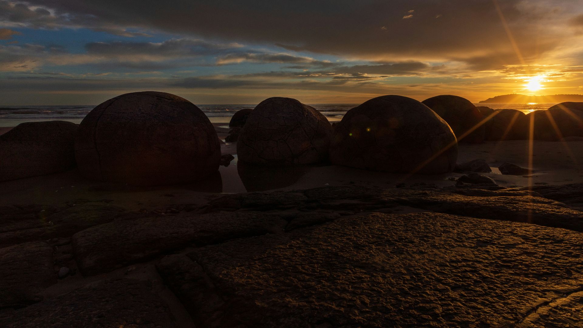 silhouette of two person standing on brown sand during sunset