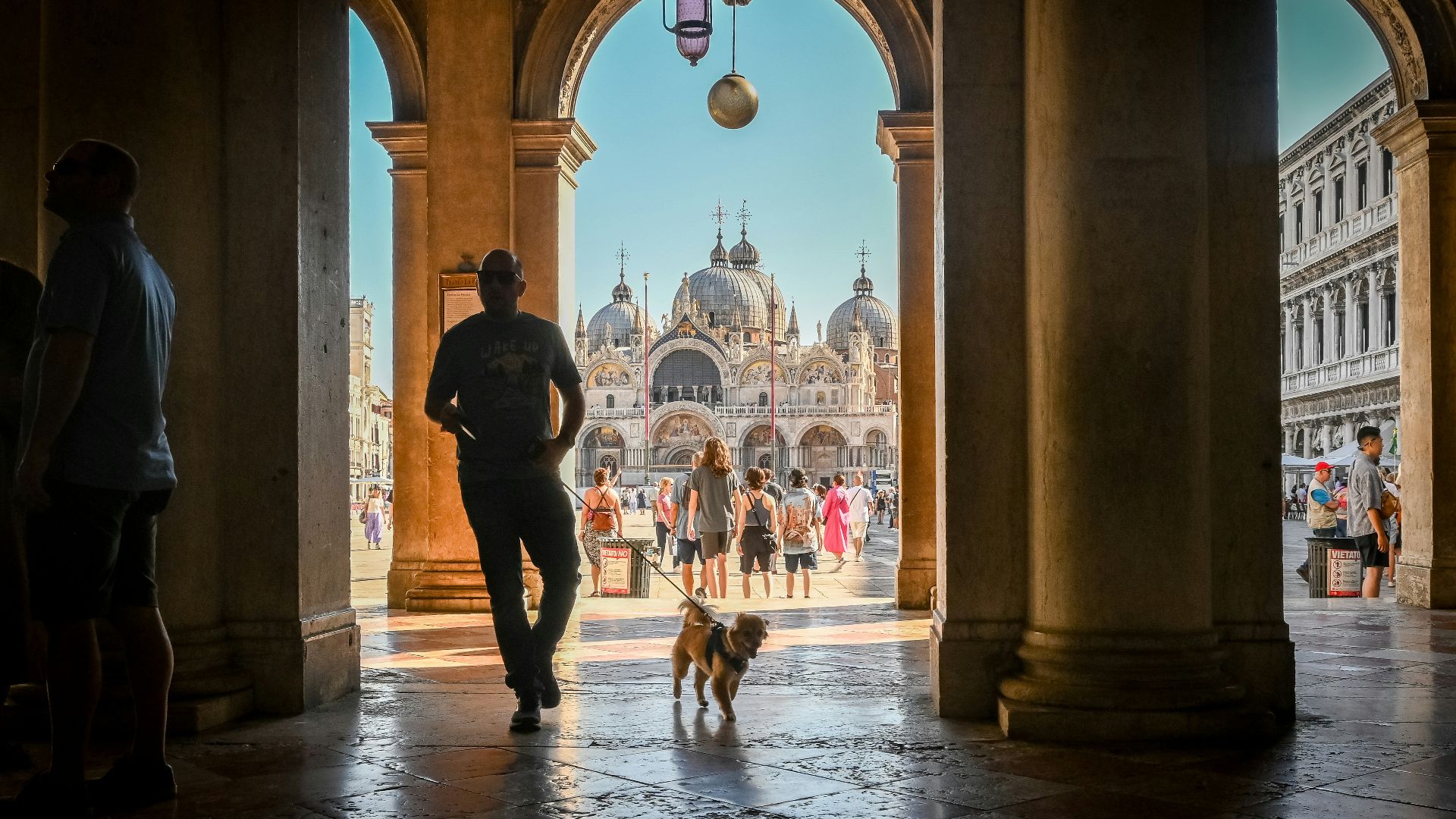 a man walking a dog through an archway