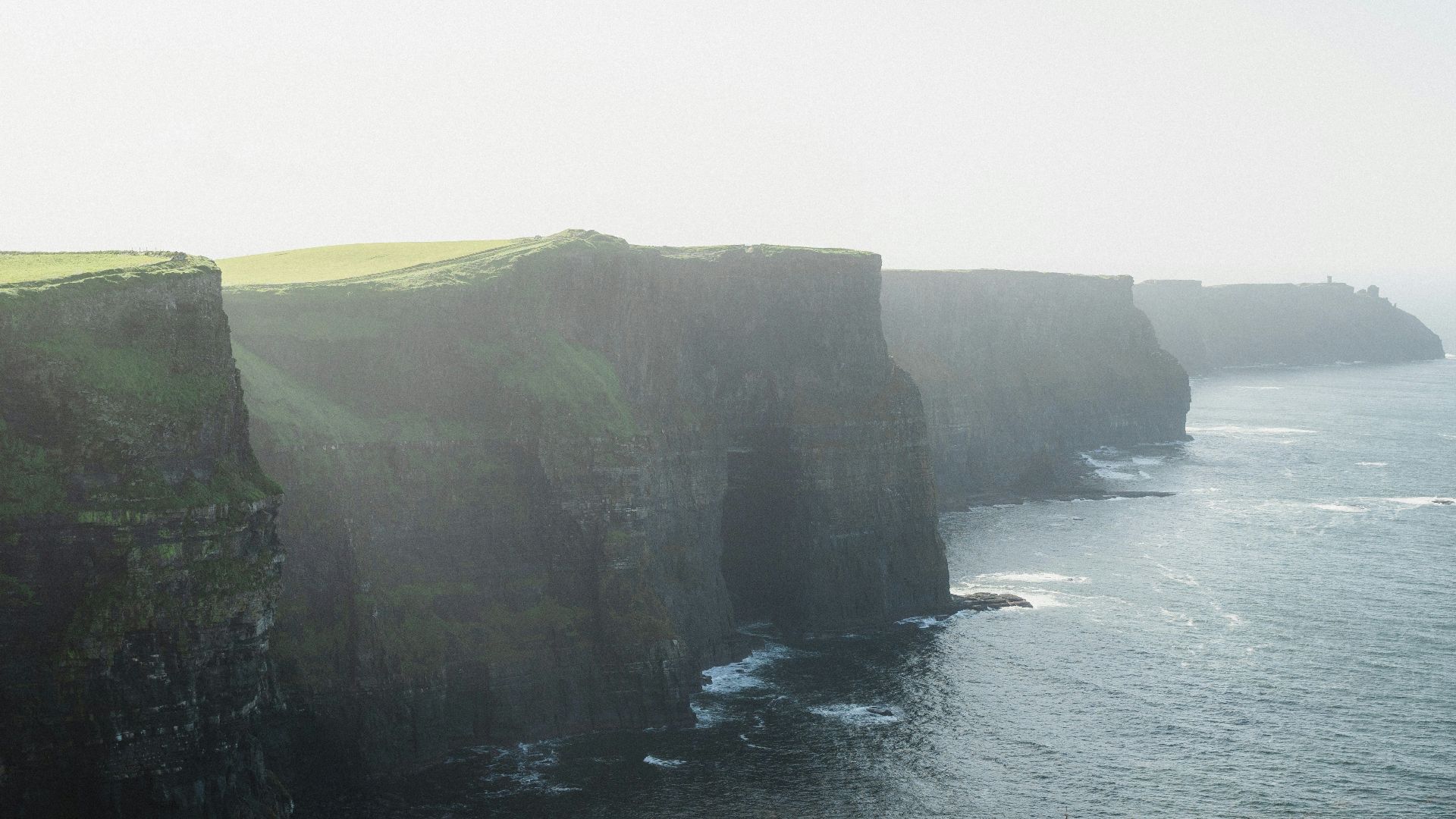 a large cliff with a grassy area on the side of it