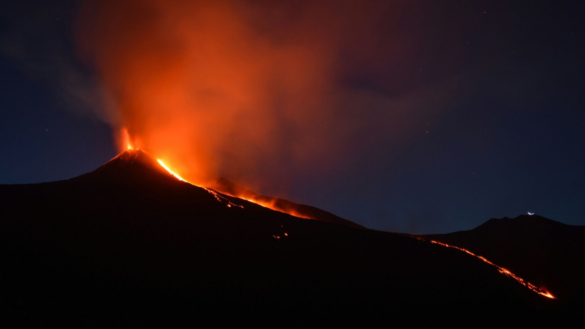 black mountain with flowing lava at nighttime