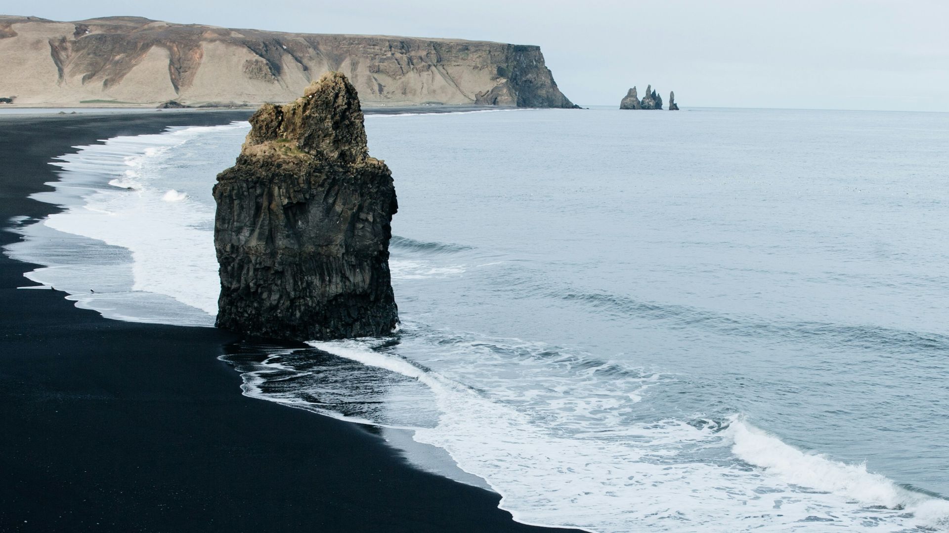 brown monolith rock on seashore
