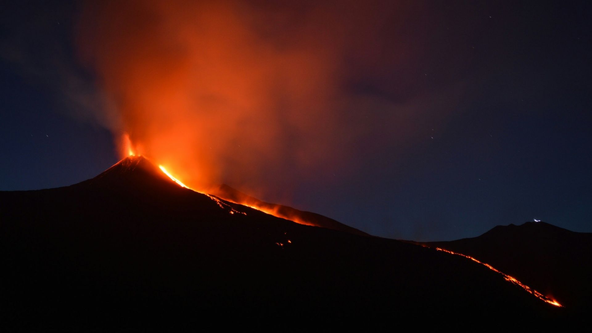 black mountain with flowing lava at nighttime