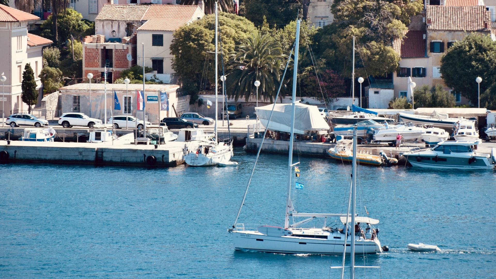 white sail boat on body of water near city buildings during daytime