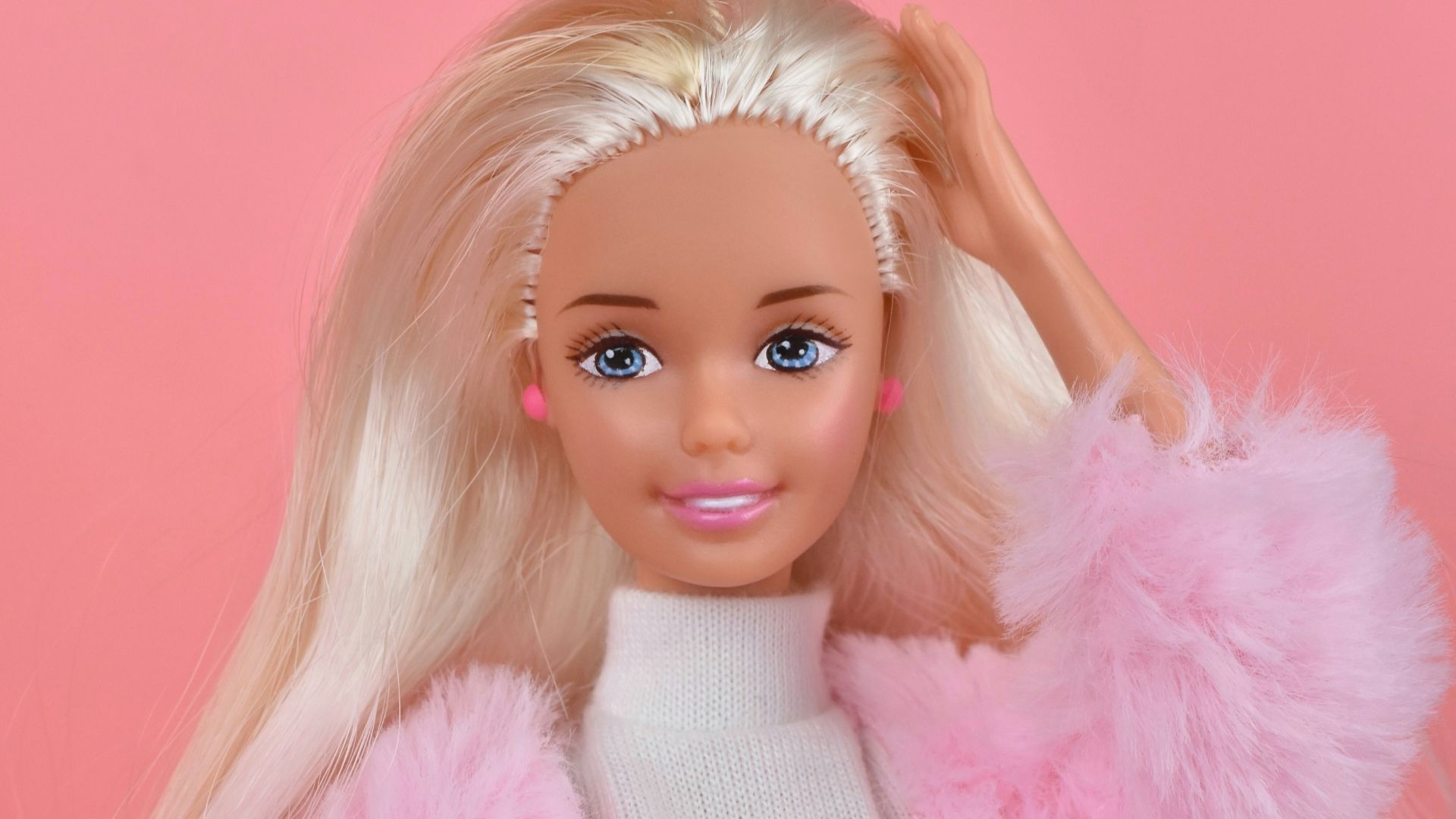 A barbie doll with blonde hair and pink pants