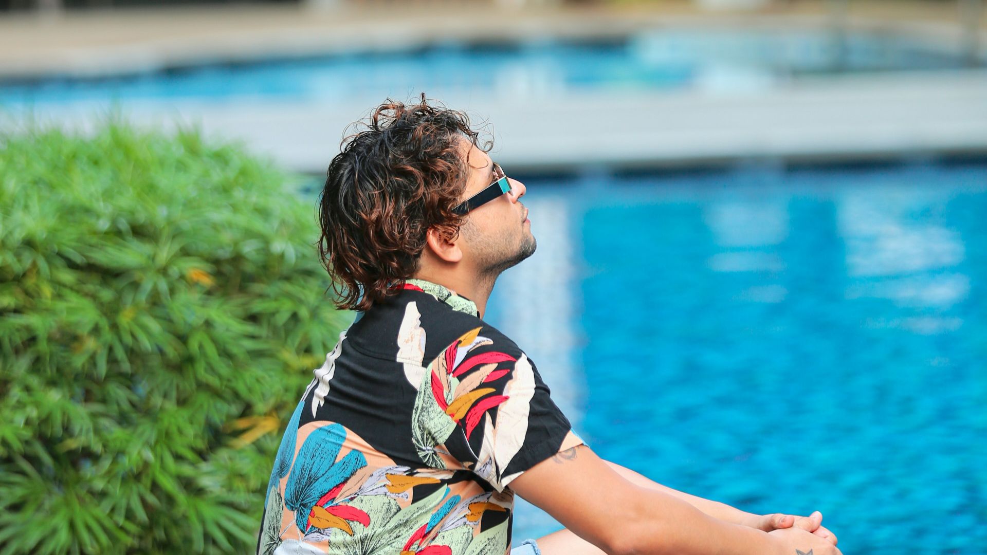 a man sitting on the edge of a swimming pool