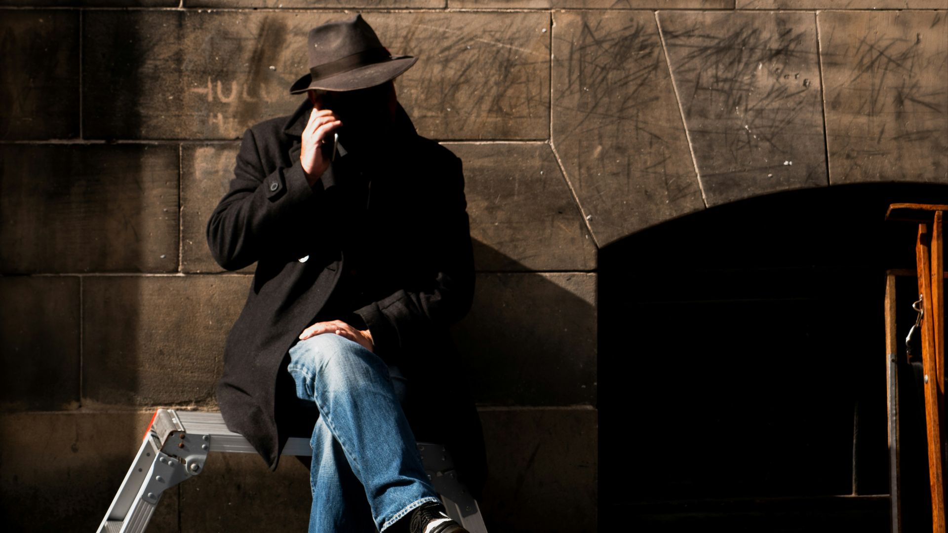 man sitting on stool near wall