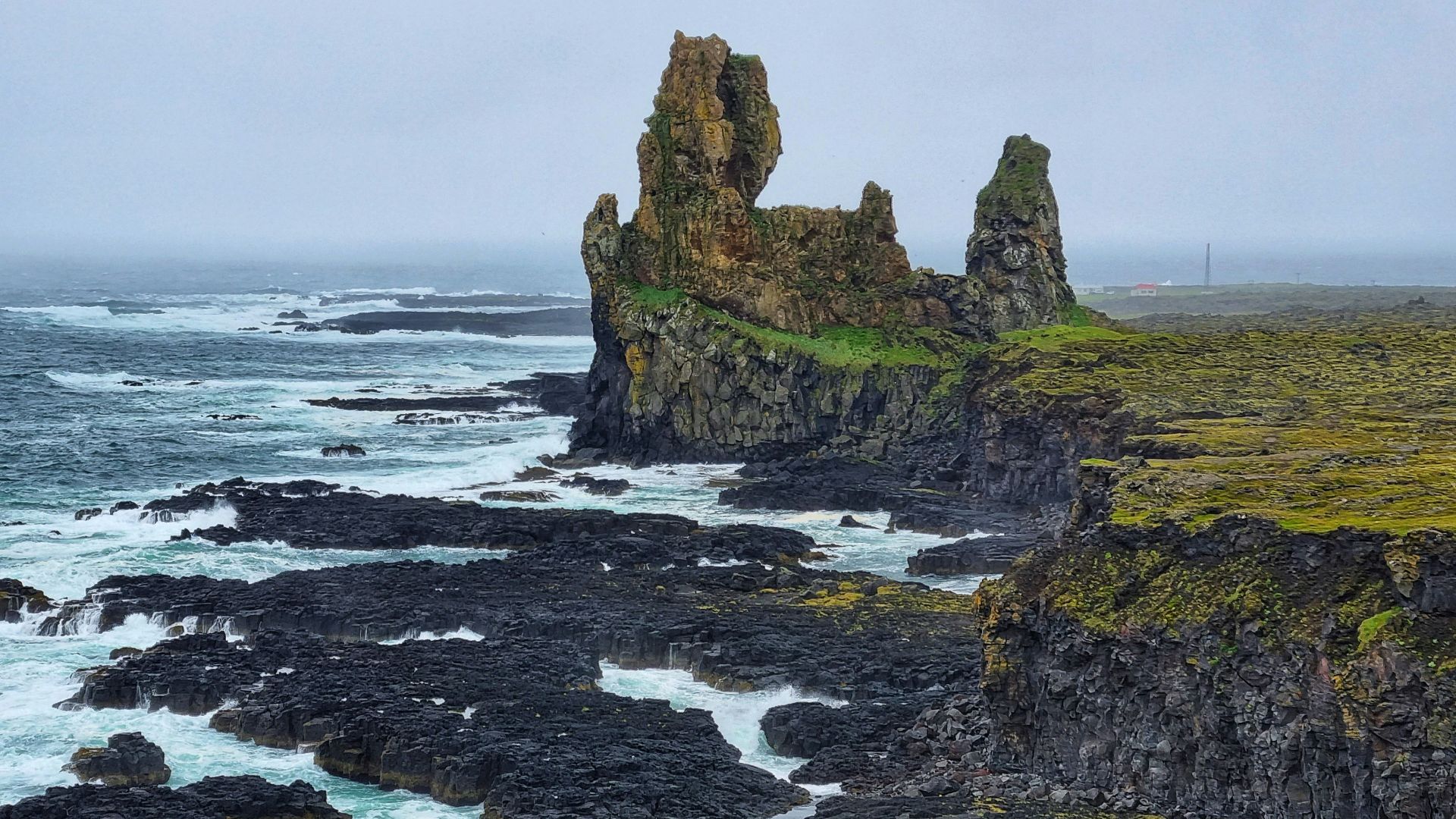 brown and green rock formation on sea during daytime