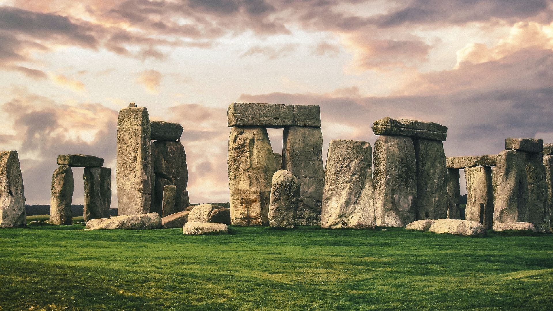 gray rock formation on green grass field under gray cloudy sky