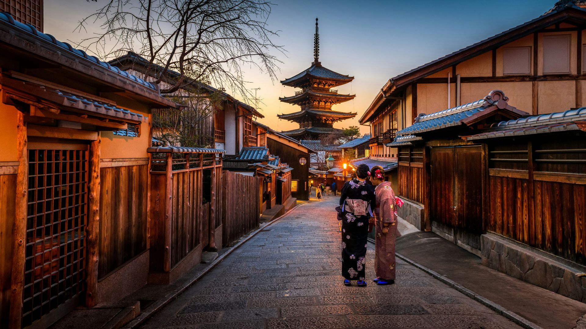 two women in purple and pink kimono standing on street