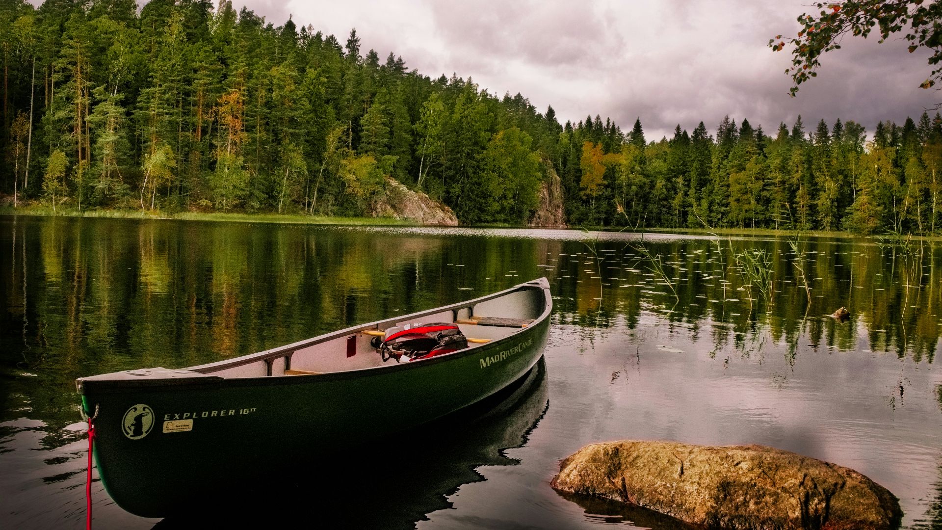 red and white canoe on lake near green trees under white clouds during daytime