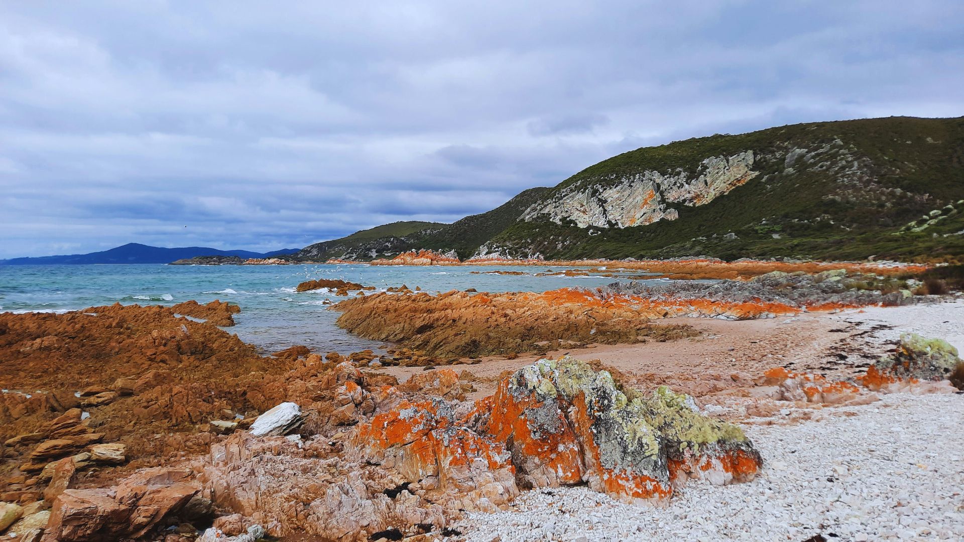 A rocky beach with a body of water in the background