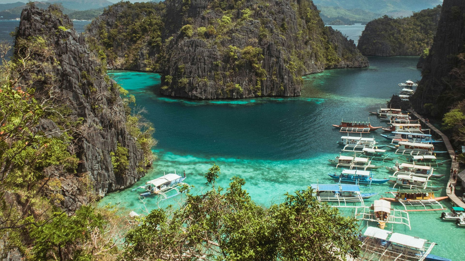 green and brown mountain beside body of water under blue sky during daytime