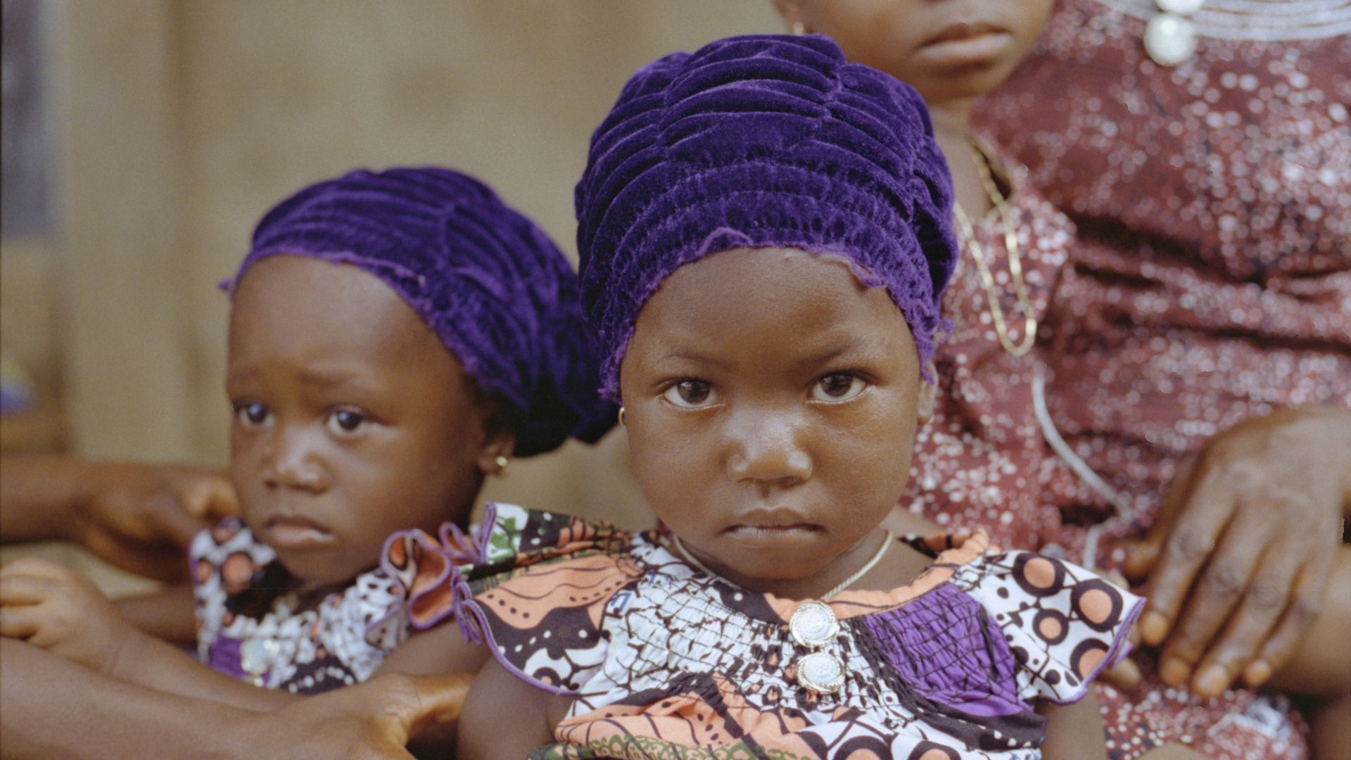 woman carrying baby in white and brown floral dress