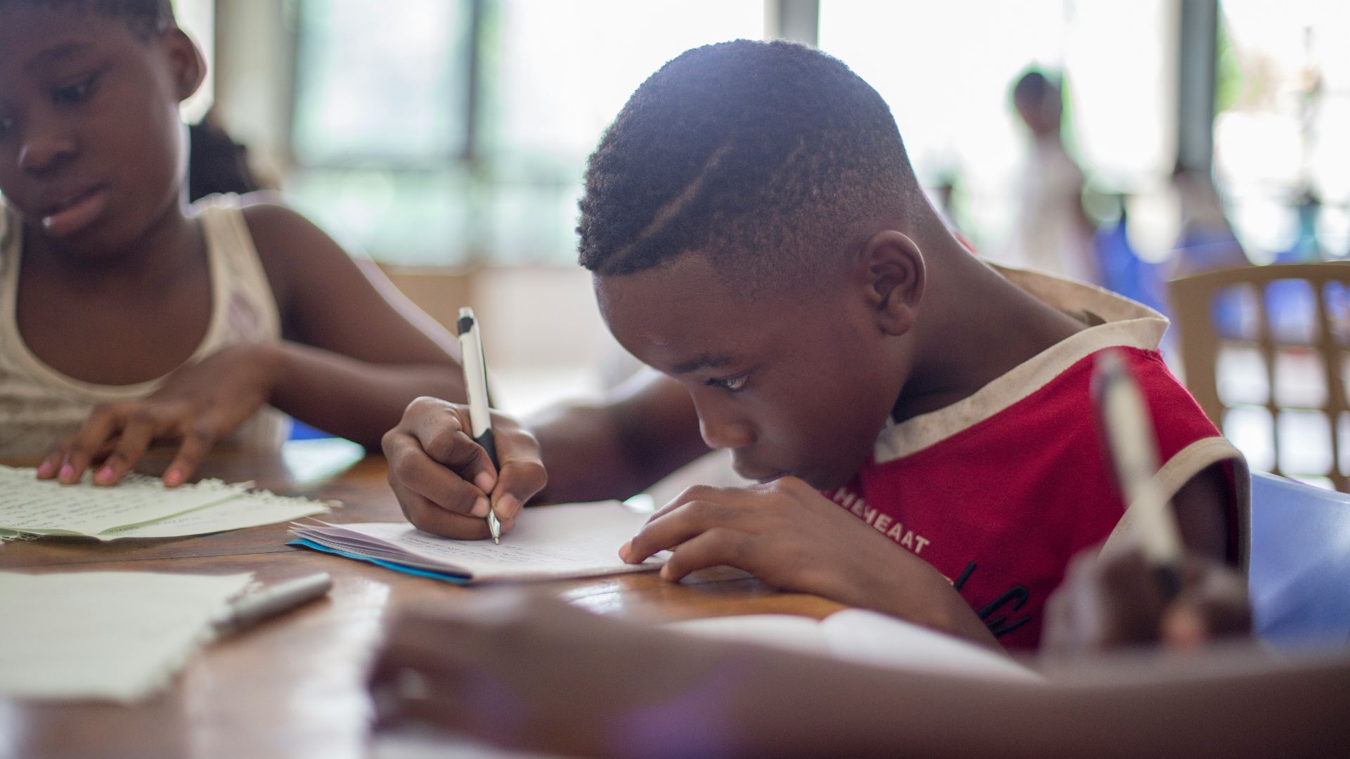 boy writing on printer paper near girl