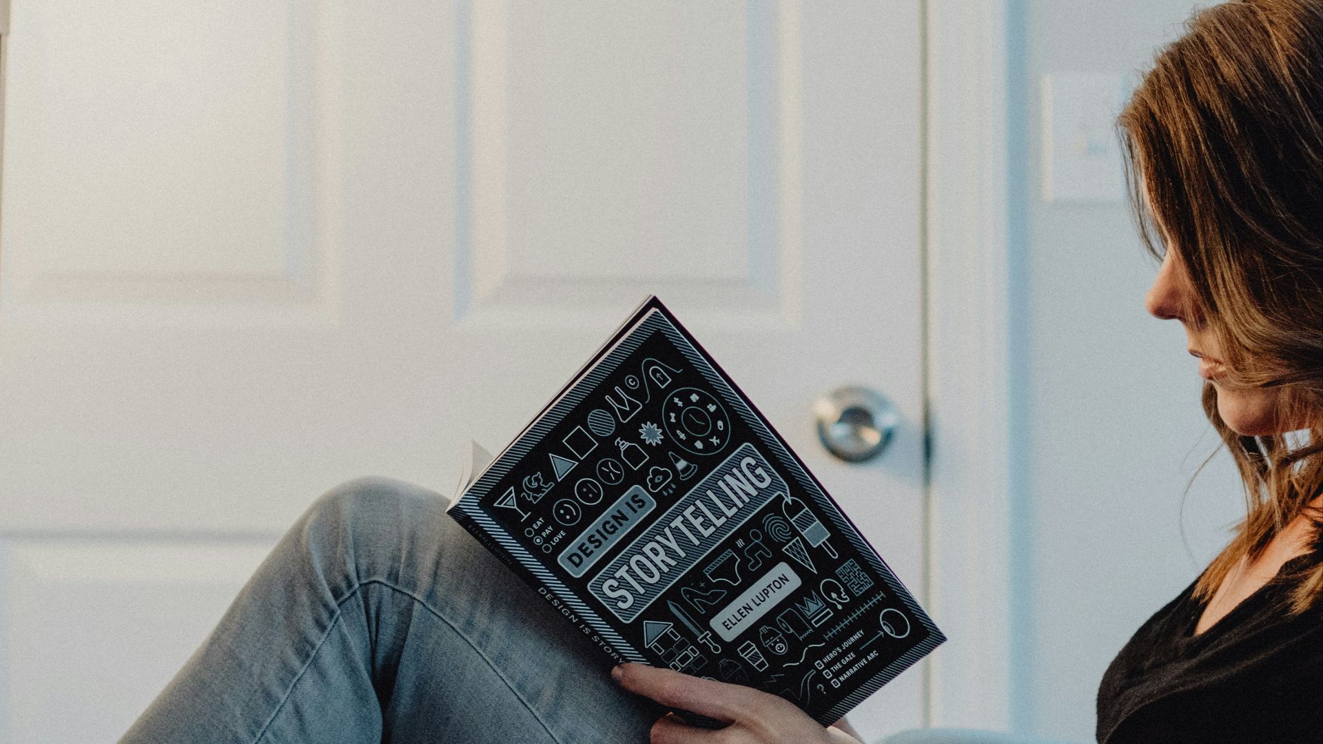woman in black long sleeve shirt and blue denim jeans sitting on white table