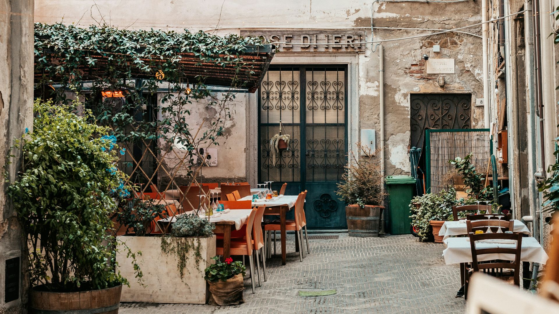 an alley way with tables and chairs in front of a building