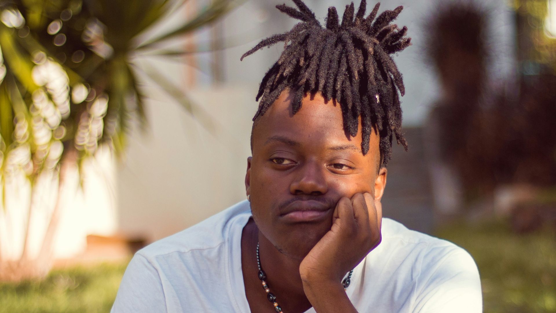 man in white crew neck t-shirt sitting on brown wooden chair