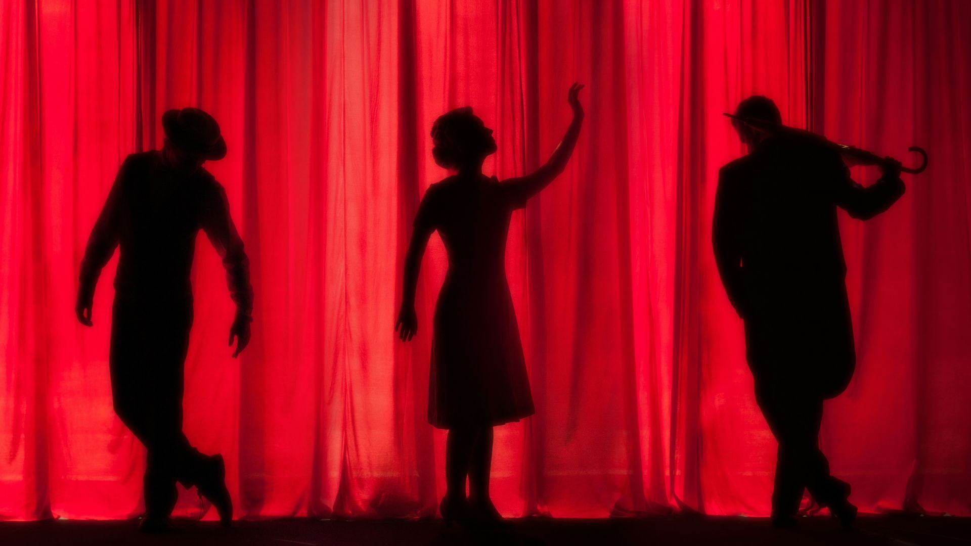 silhouette of three performers on stage