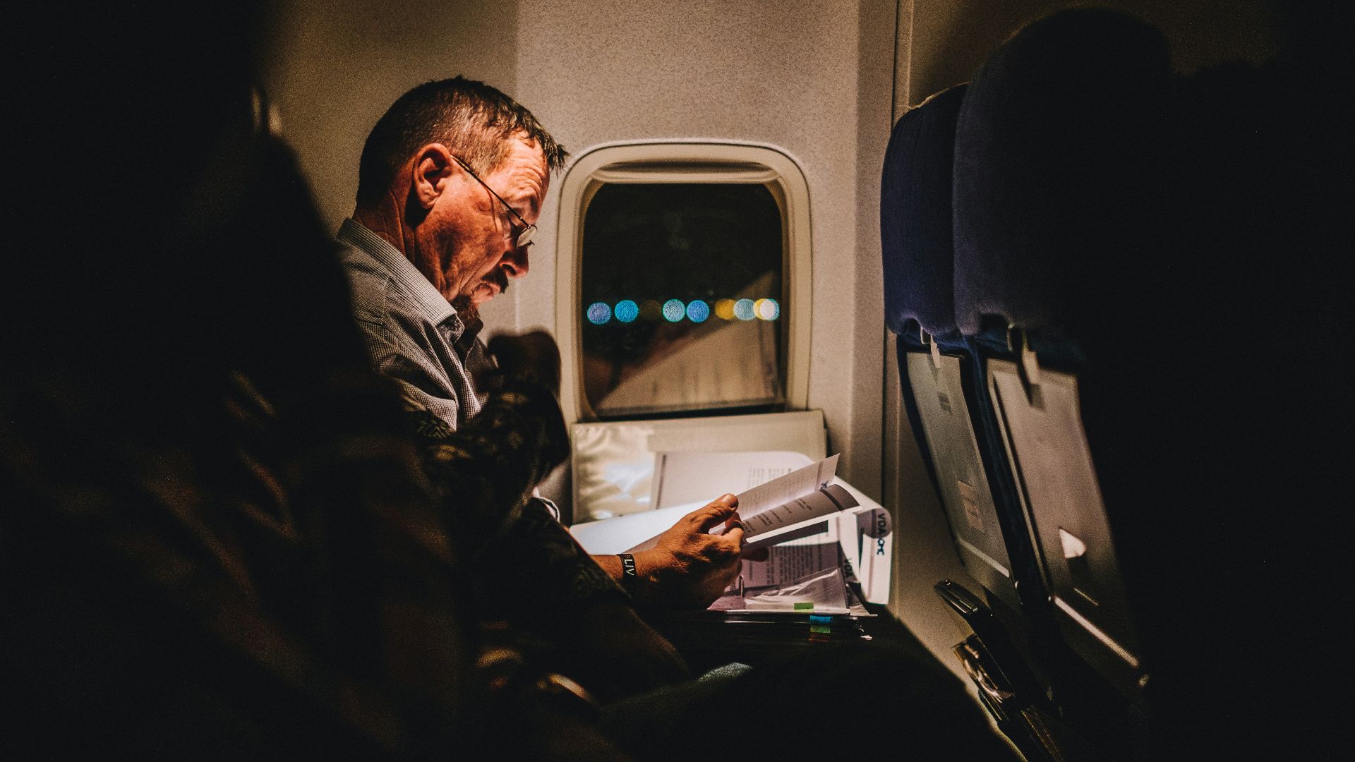 man reading book inside vehicle
