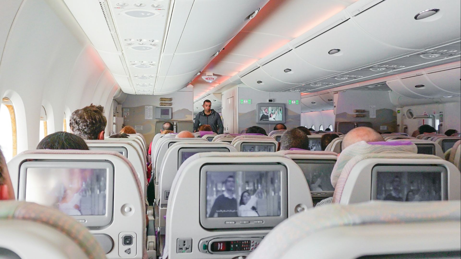 man walking down the aisle of airplane