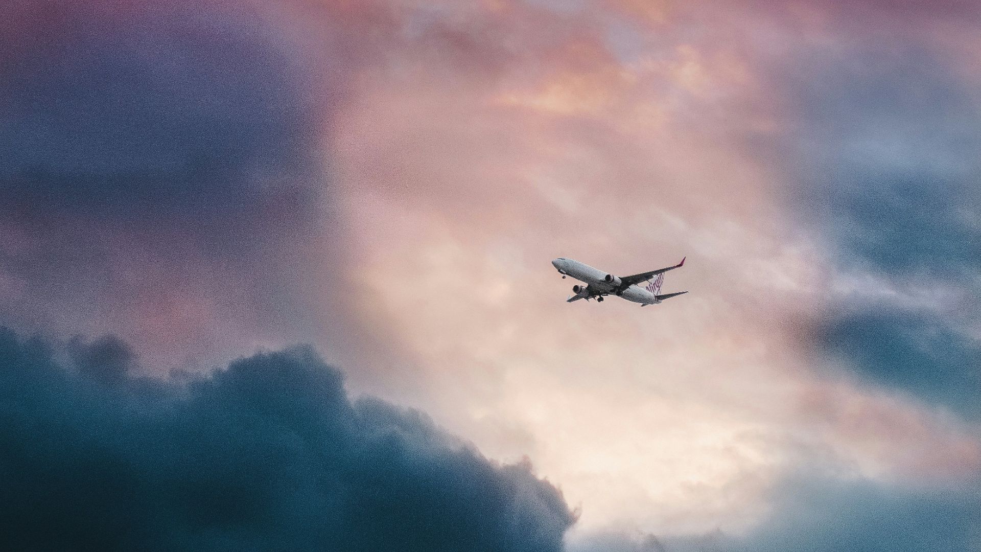 white plane flying over gray clouds