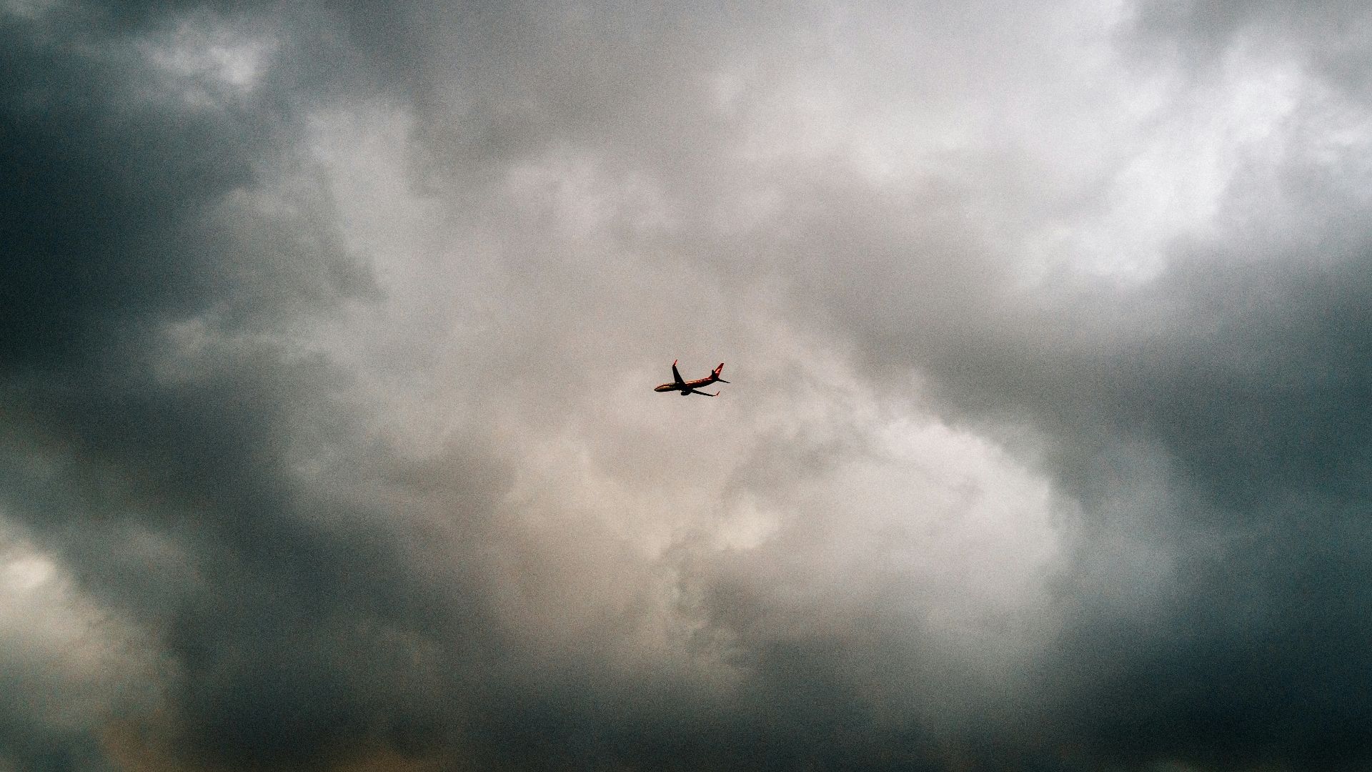 A plane flying through a cloudy sky over a field