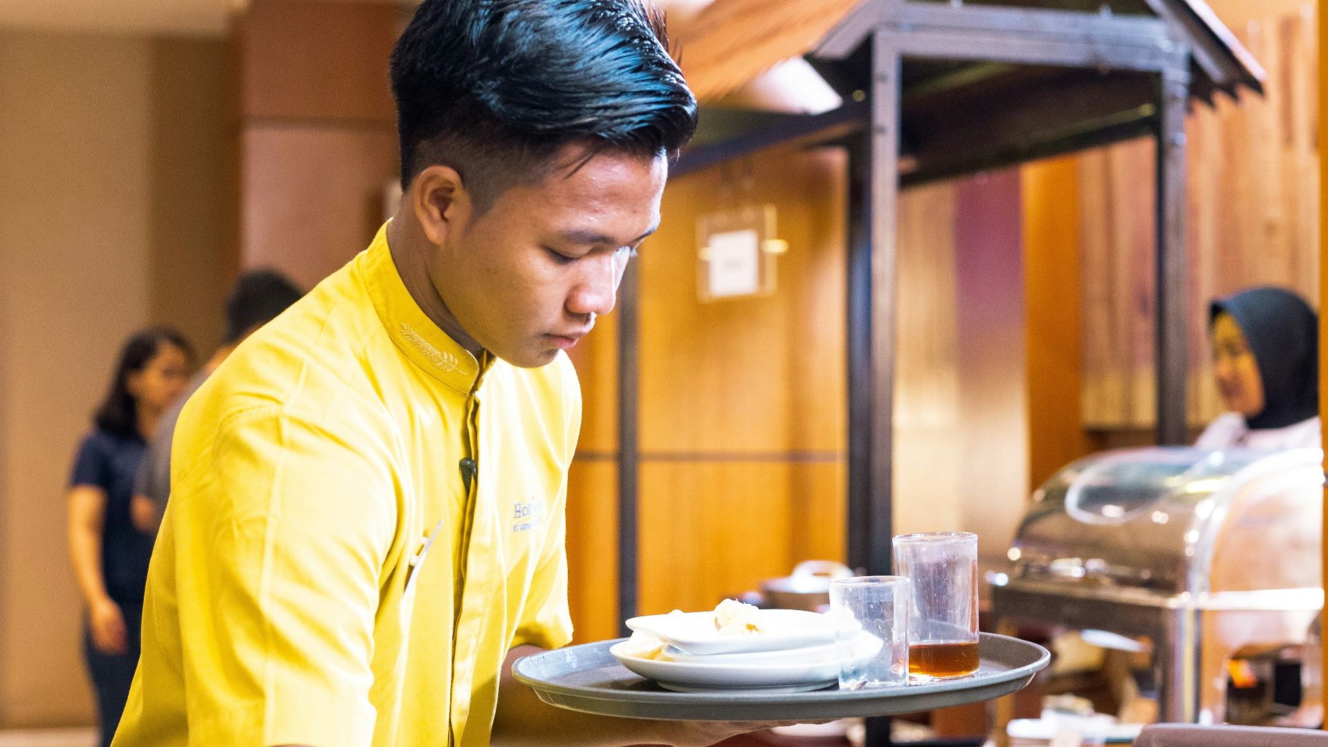 man in yellow polo shirt standing in front of table