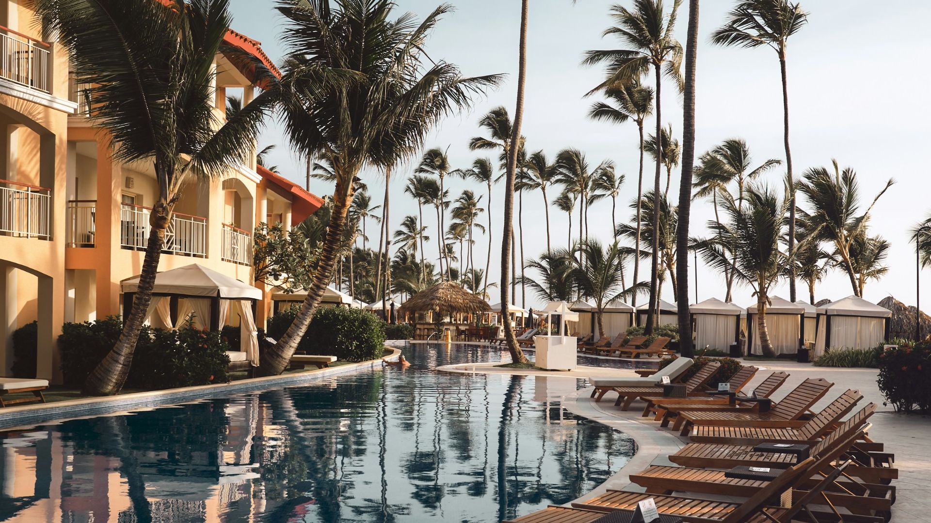 brown wooden lounge chairs near pool surrounded by palm trees