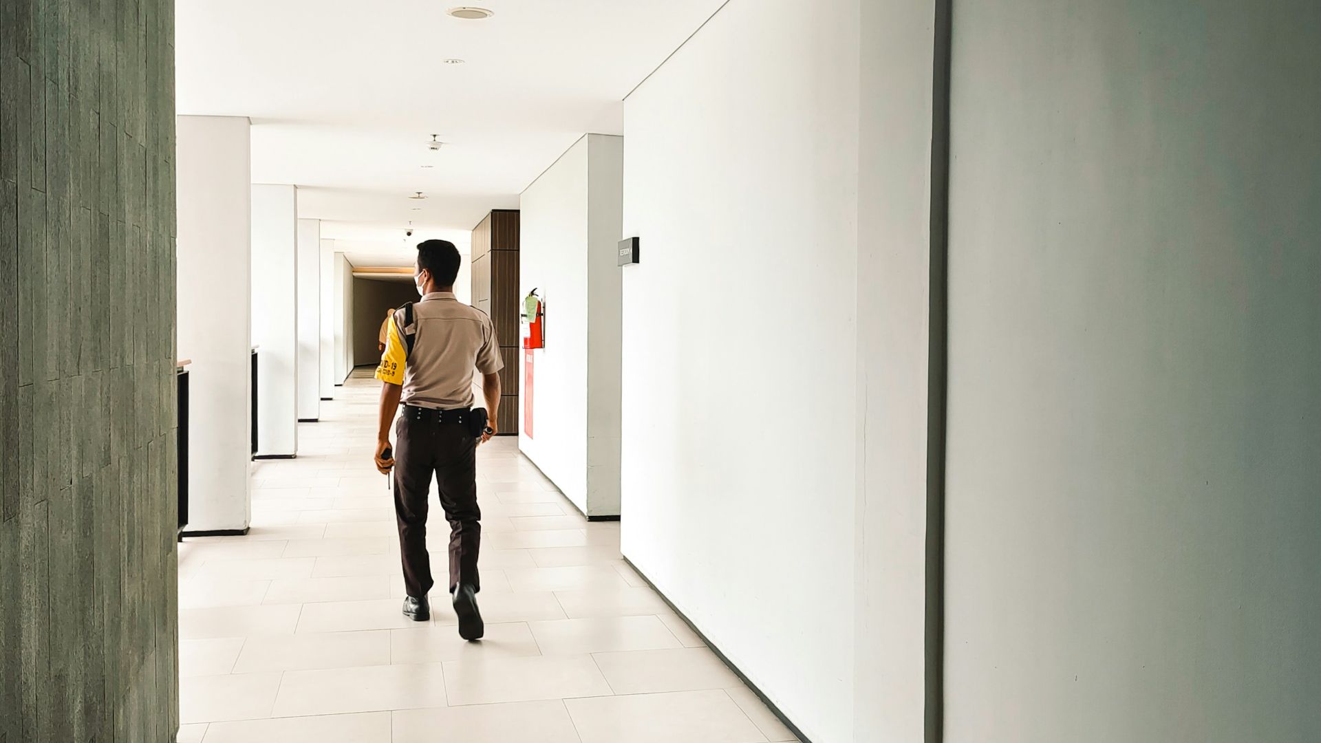 a man walking down a long hallway between two walls