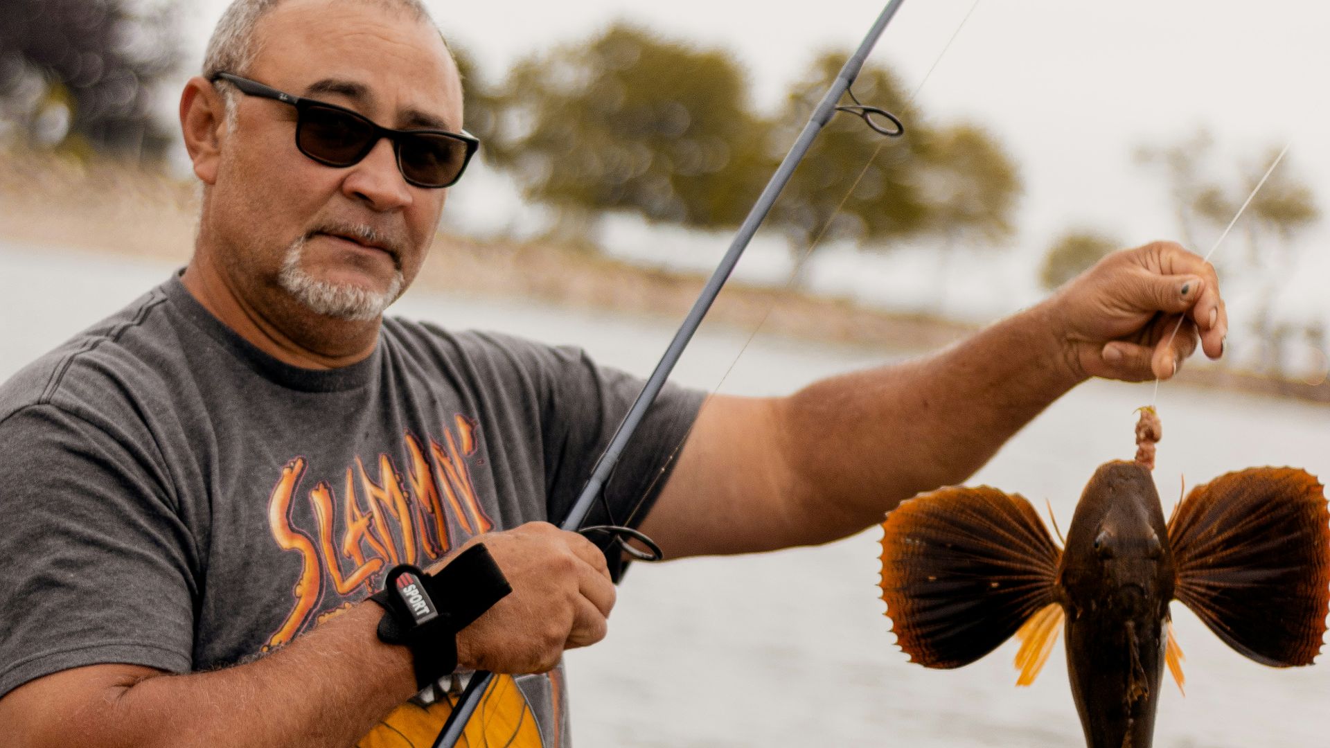man in gray crew neck t-shirt holding brown fish during daytime
