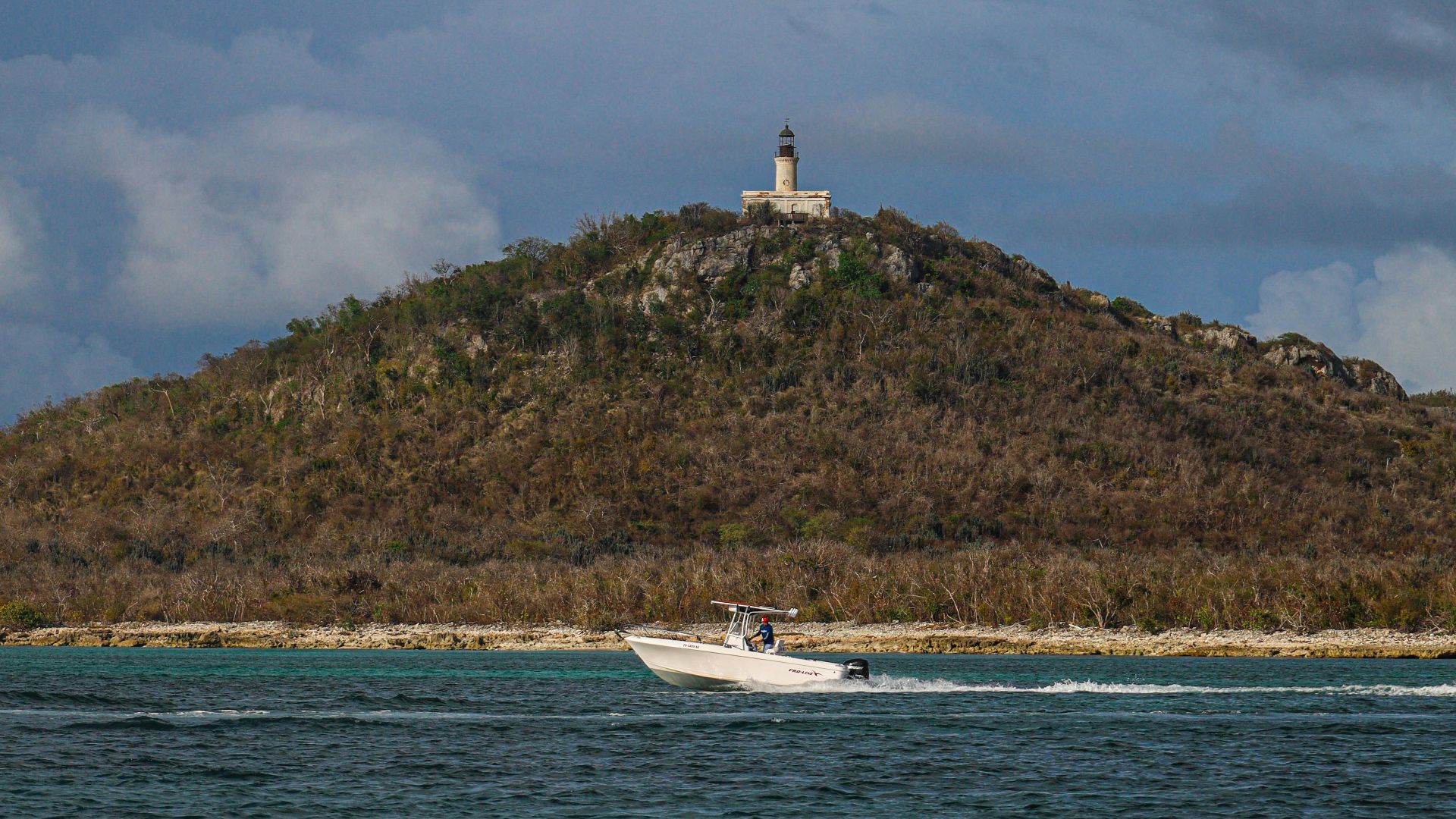 white boat on sea near green mountain under white clouds during daytime