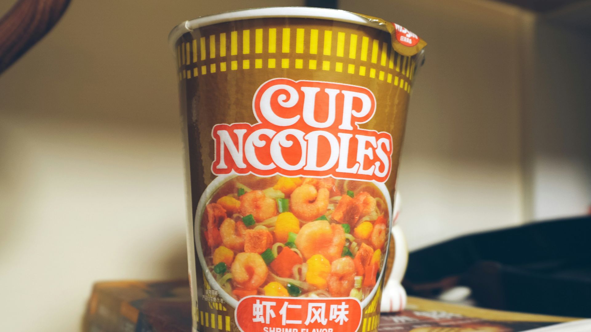 a cup of noodles sitting on top of a stack of books