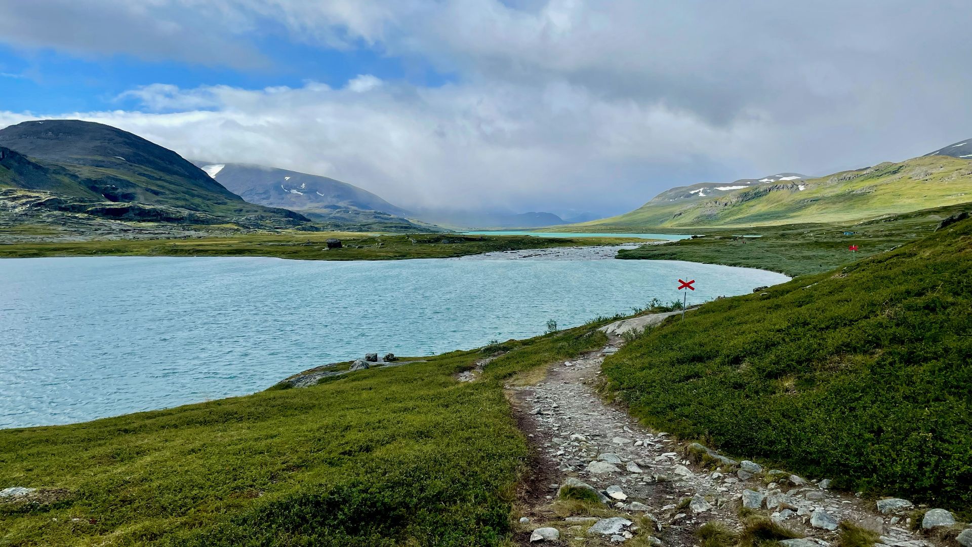 a path leading to a body of water with mountains in the background