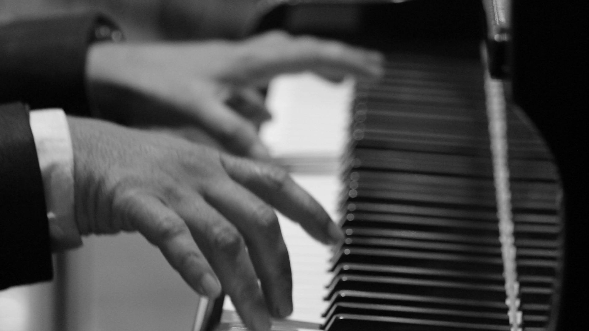 grayscale and selective focus photo of person playing piano
