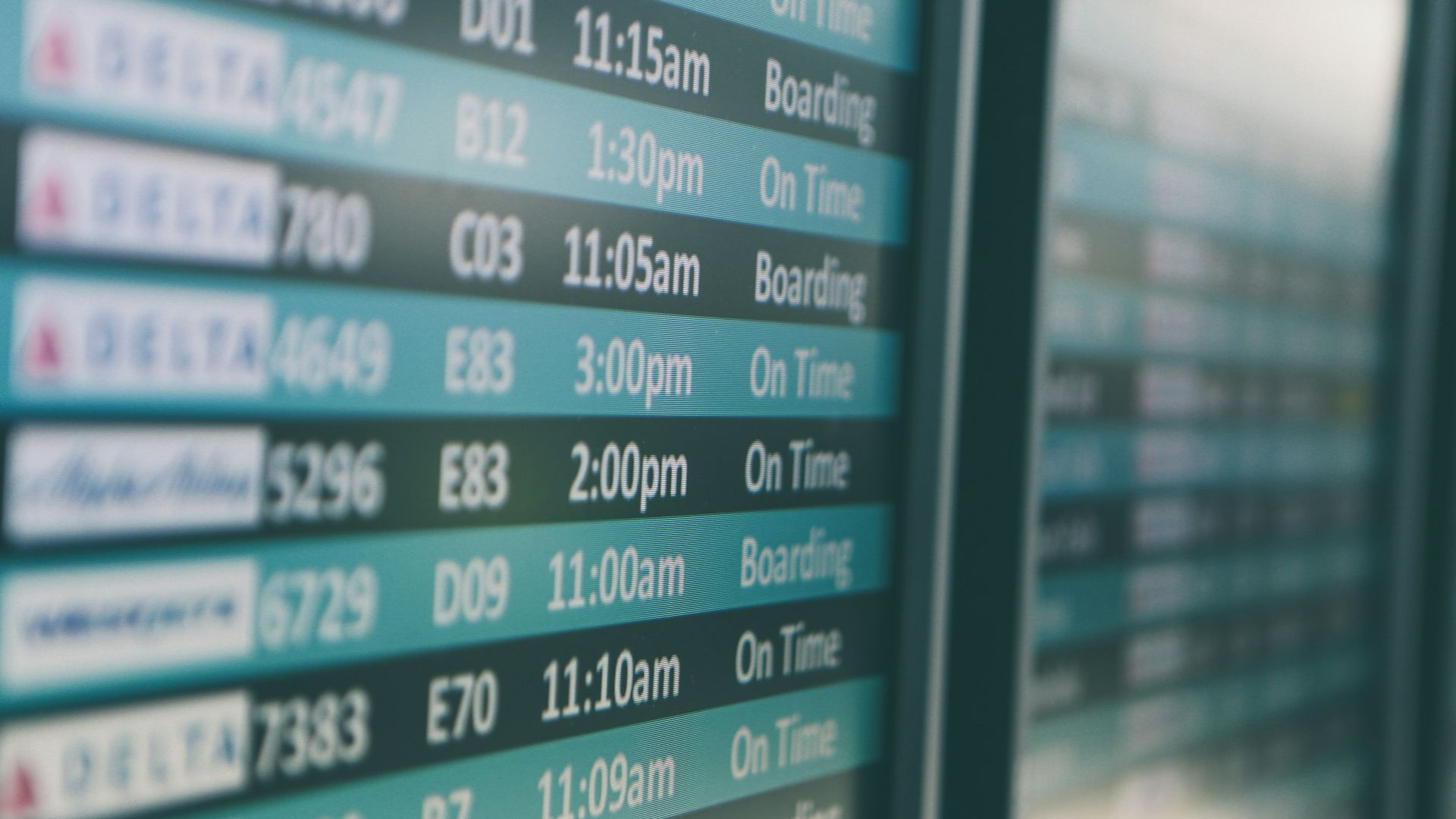 Airport departures timetable showing Delta and Alaska Airlines flights on time and boarding