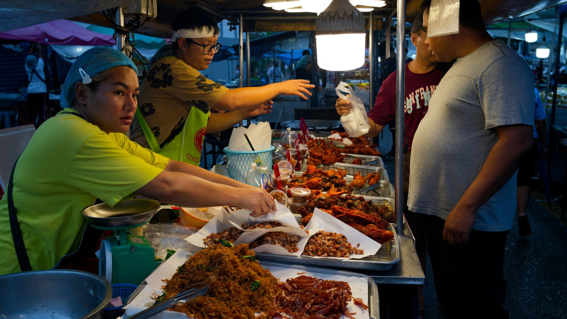 Vendors serve food at a busy night market stall.