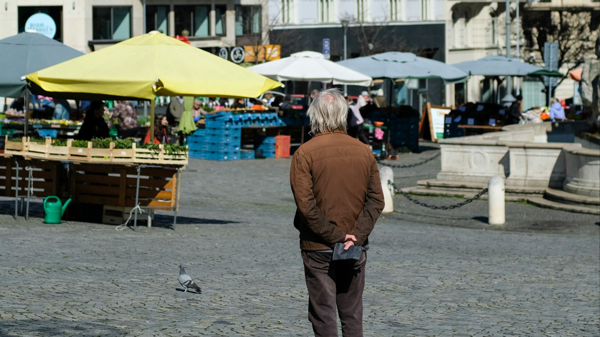 A man stands in a european town square.