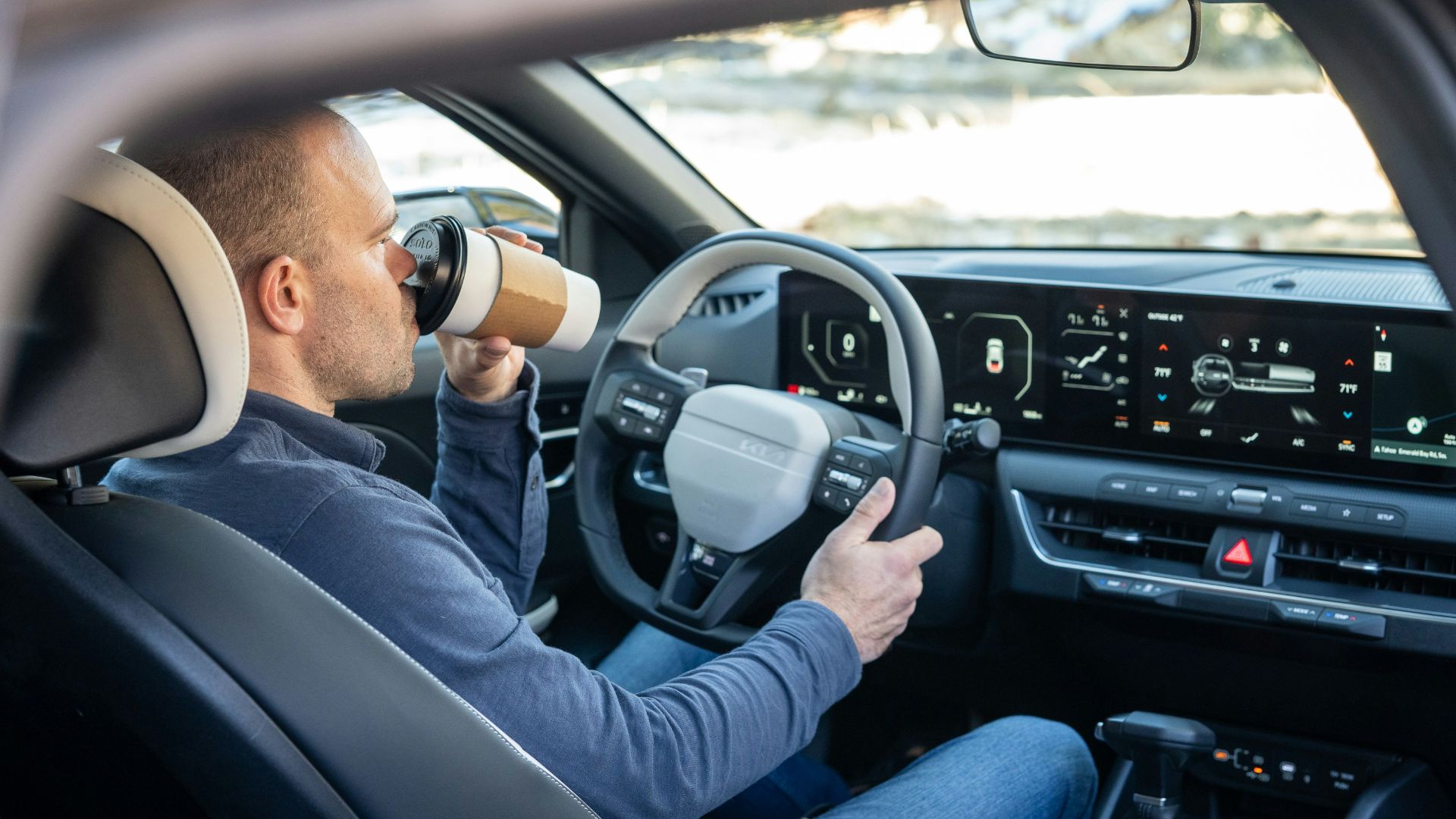 A man driving a car with a cup in his hand