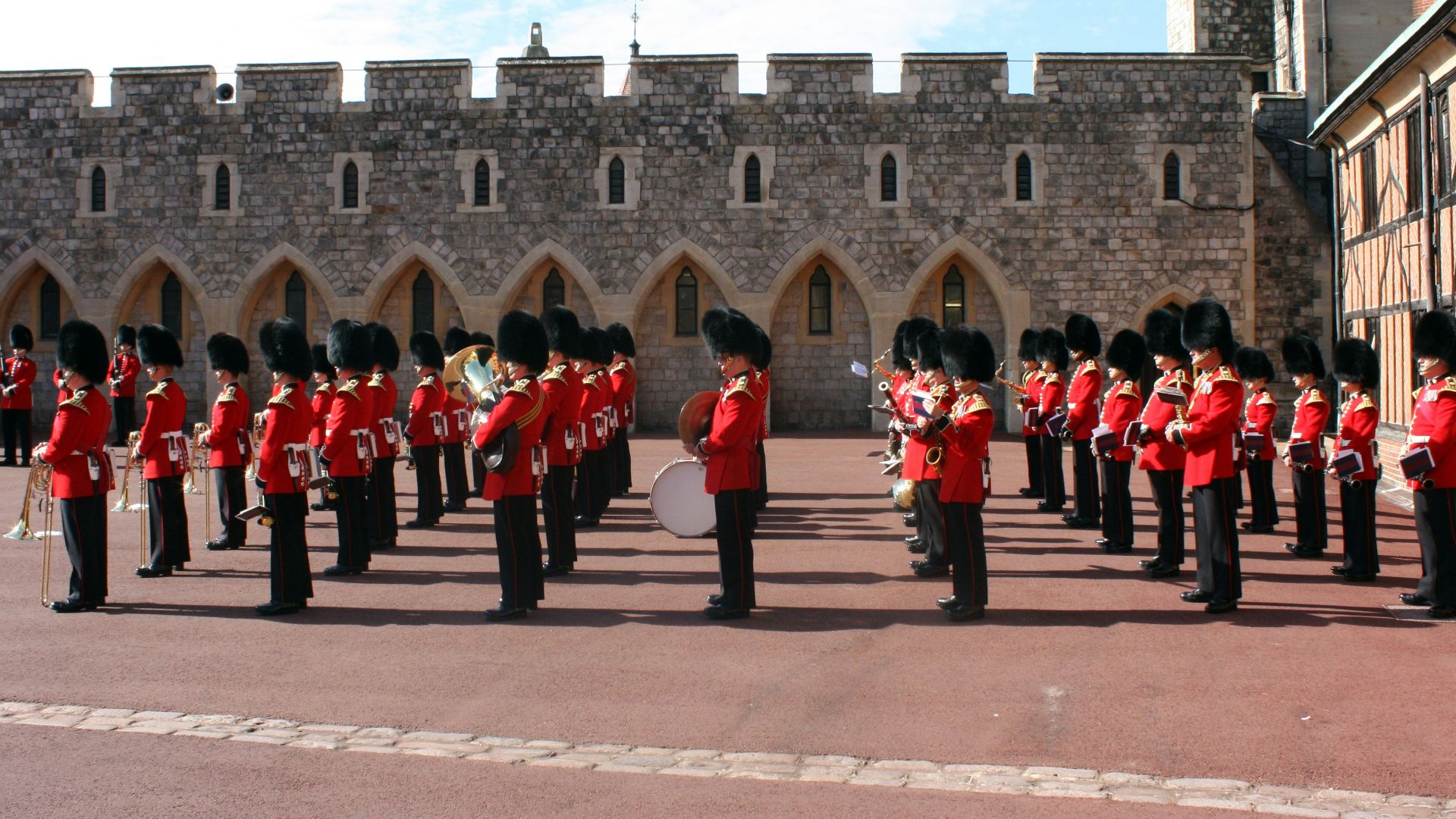 people in red and black uniform standing near brown concrete building during daytime