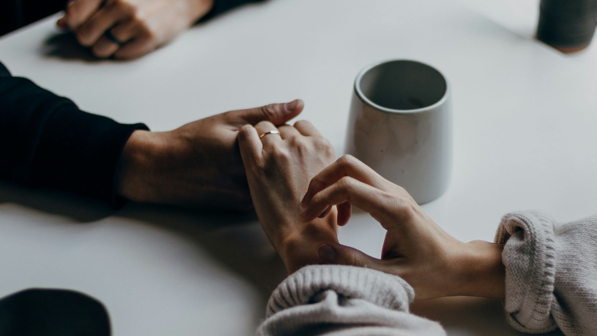 person in black long sleeve shirt holding white ceramic mug
