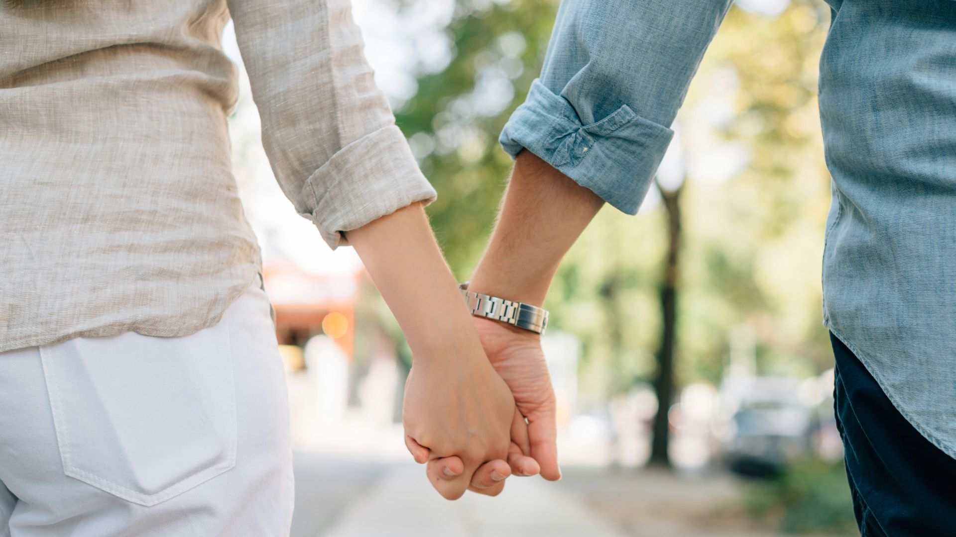 man and woman holding hands together in walkway during daytime