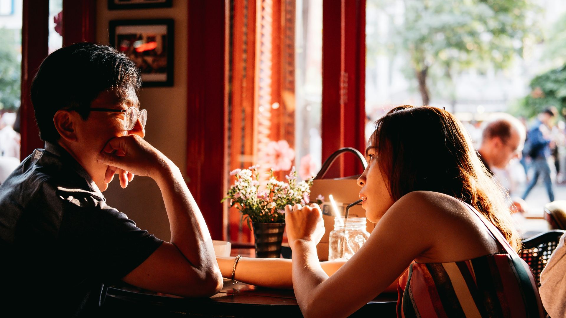 man wearing black collared top sitting on chair in front of table and woman wearing multicolored top