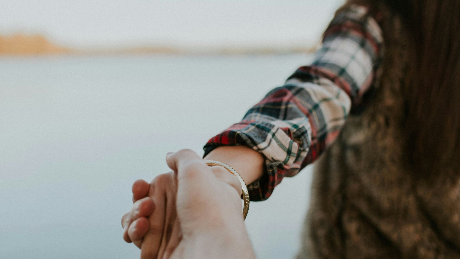 shallow focus photography of man and woman holding hands