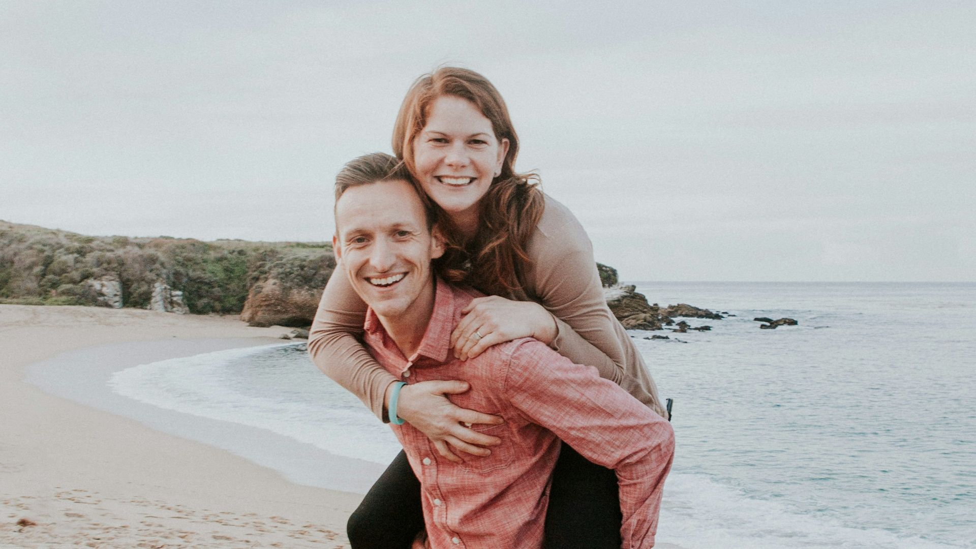 man carrying woman beside seashore