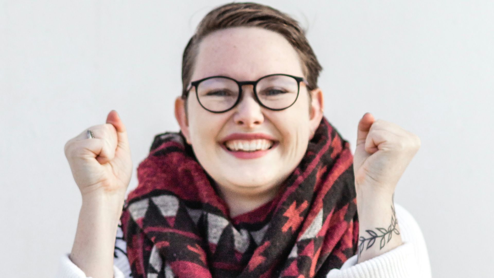woman in white sweater wearing red scarf and black framed eyeglasses