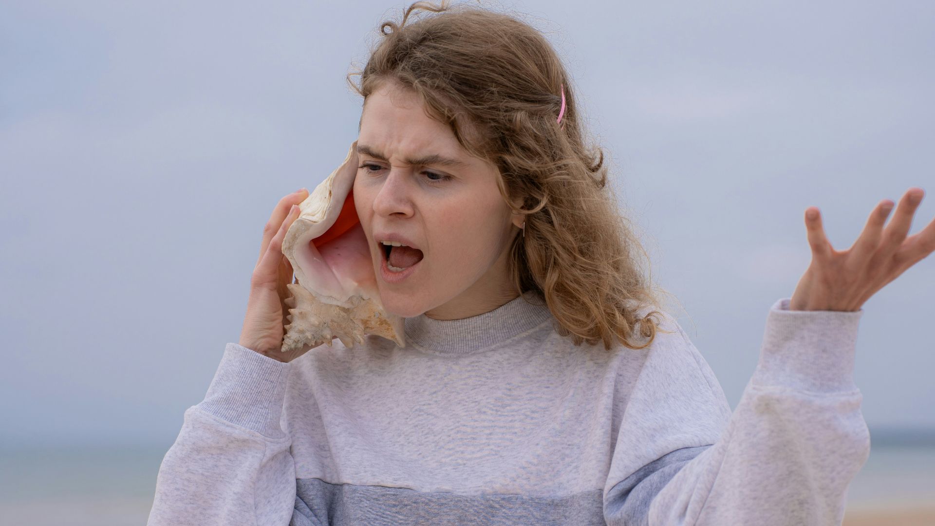 a woman on the beach holding a cell phone to her ear