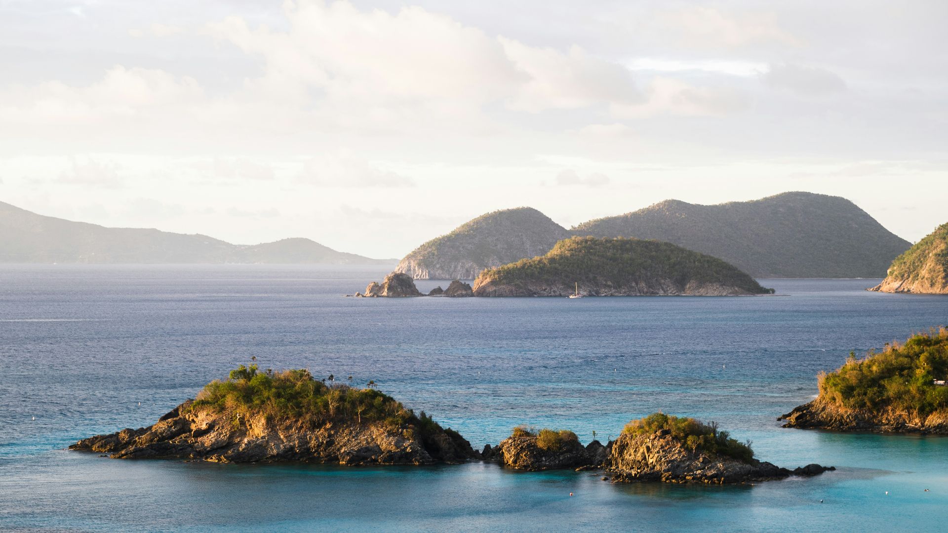 brown and green island on blue sea under white clouds during daytime