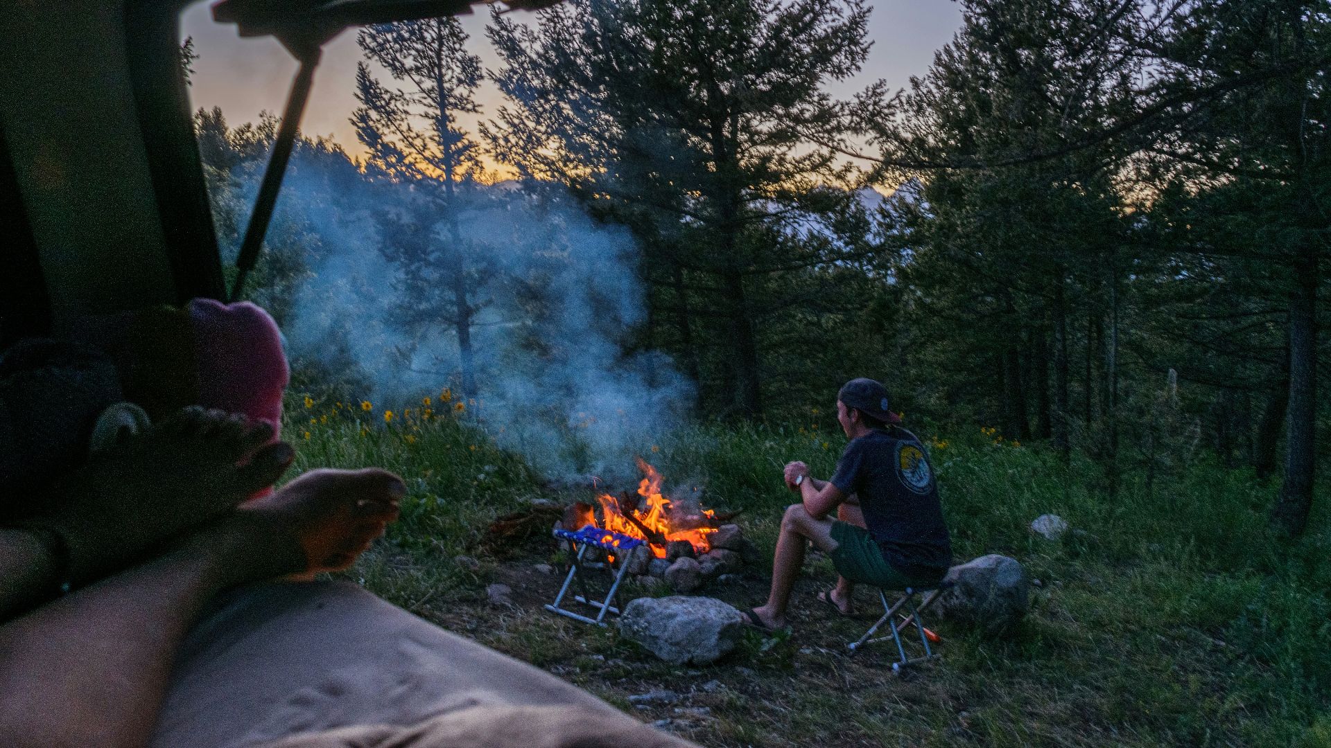 a man sitting in a chair next to a campfire