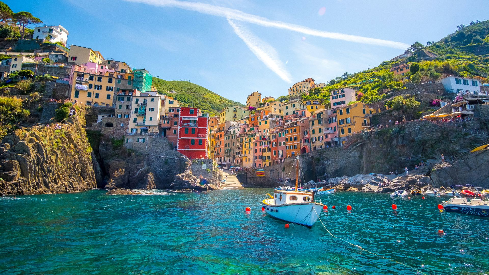 blue fishing vessel near houses on mountain