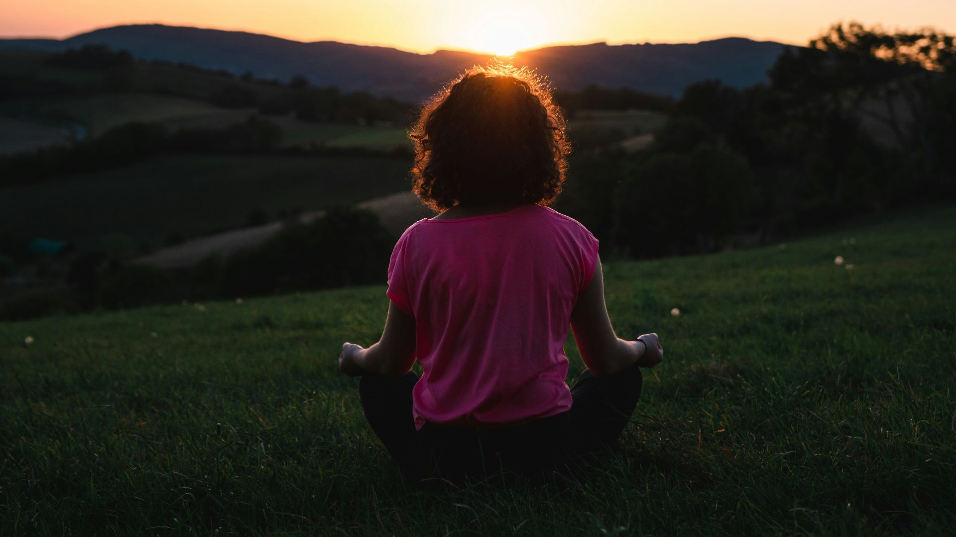 woman squatting in grass during golden hour